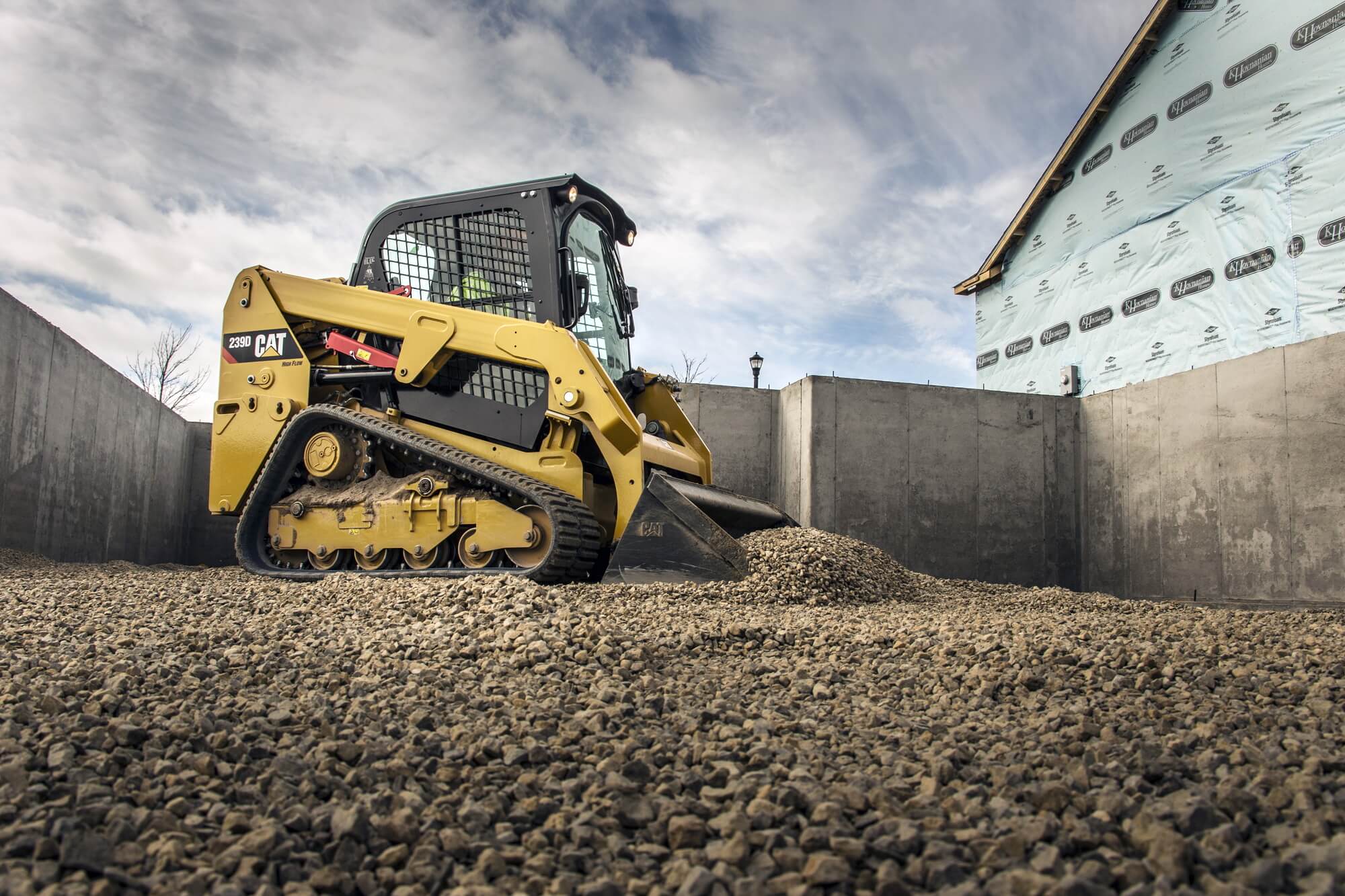 CAT compact track loader dragging gravel for construction.